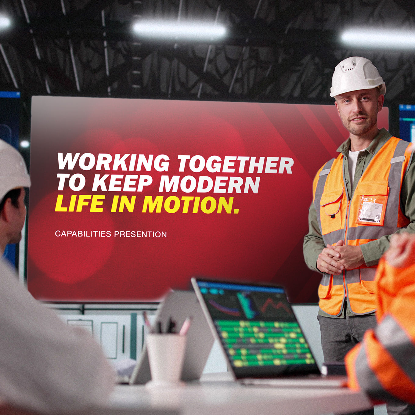 A worker in a hardhat and visibility vest is giving a presentation about MCE with the headline: Working Together to Keep Modern Life in Motion